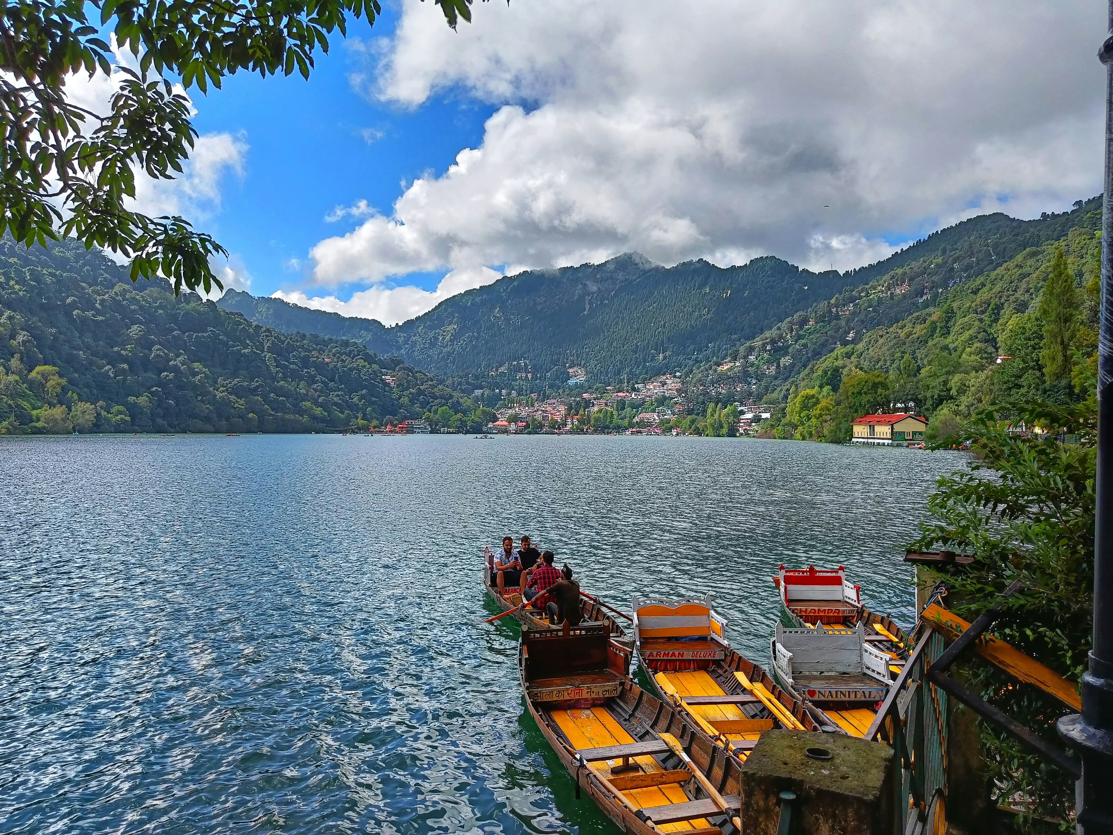 Boats on Naini Lake with mountain slopes and homes around Nainital